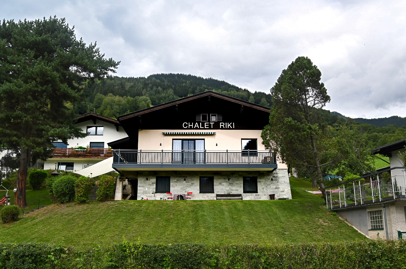 Chalet Riki mit Balkon und Garten vor bewaldeten Bergen